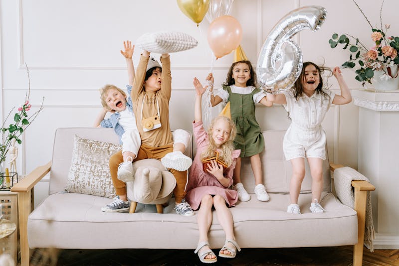 Happy kids with balloons on a sofa at a birthday celebration